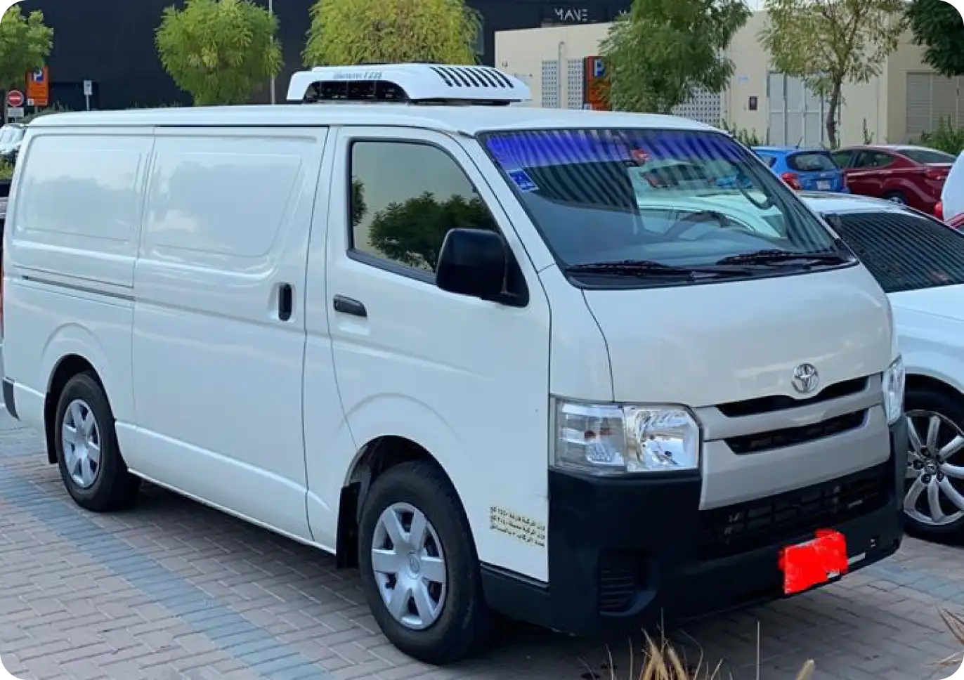 White chiller van for refrigerated transport parked in an outdoor lot with trees and buildings in the background.