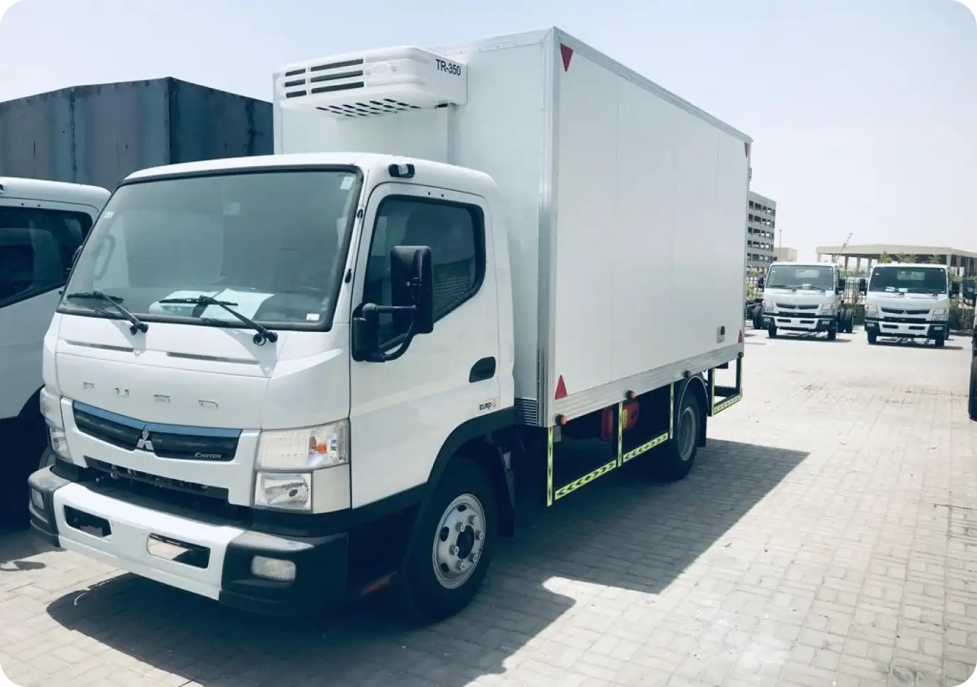 A white refrigerated delivery truck parked outdoors on a sunny day.